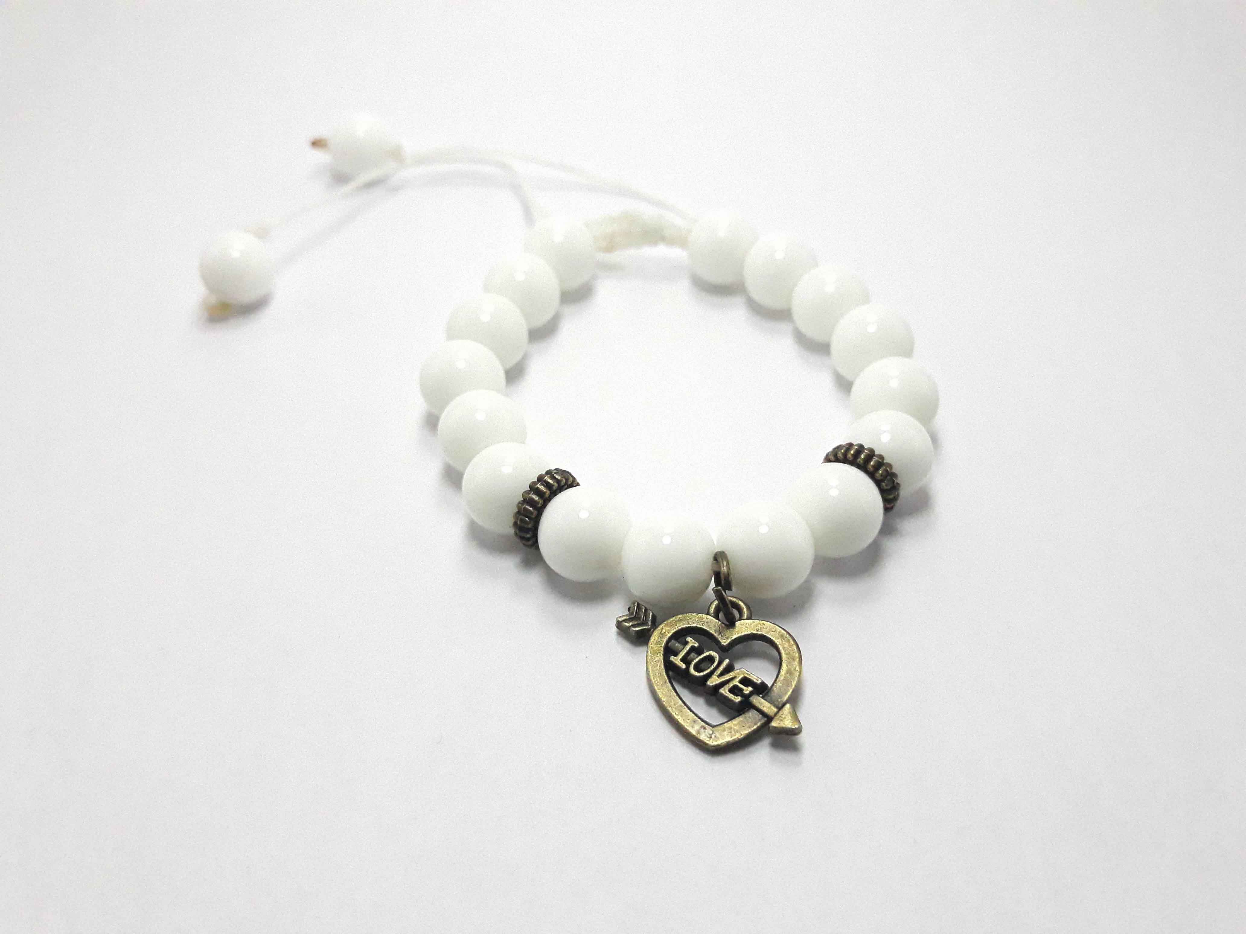 White beaded bracelet with brass heart design